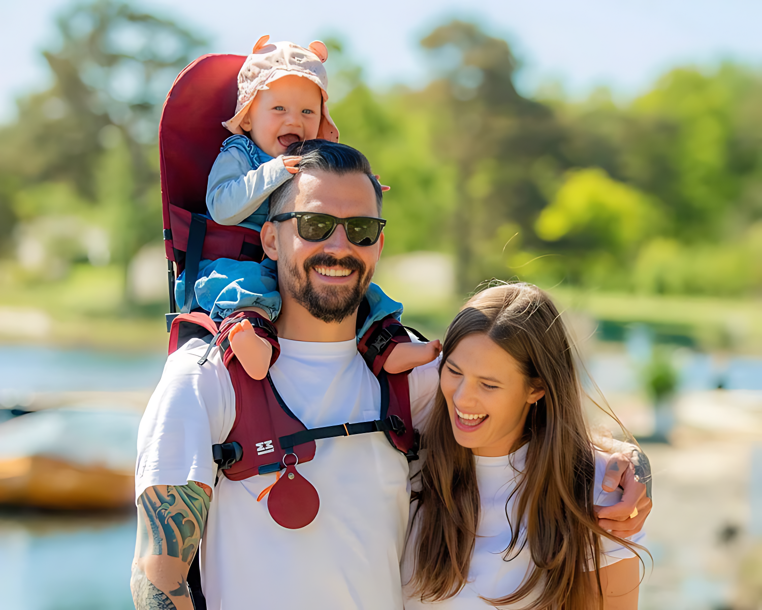 A man carrying a child in a Minimeis G4 with a woman beside them by a lake.