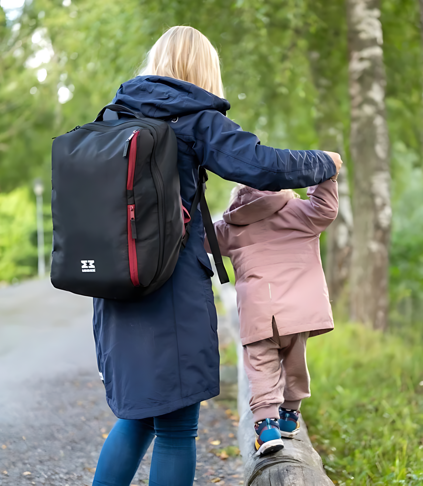 Woman with a MiniMeis backpack and child walking on a path in a forest
